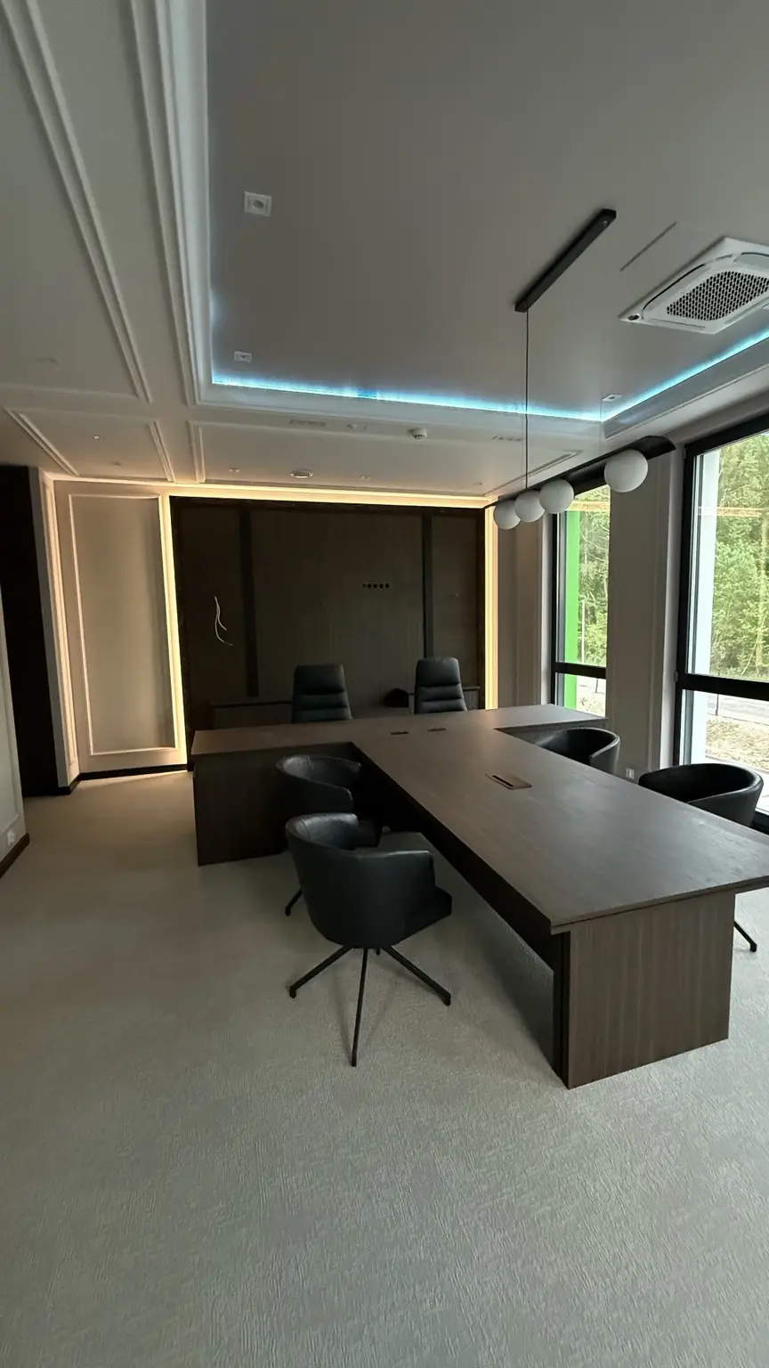 Sala konferencyjna z ciemną zabudową ścienną i stołem na wymiar
